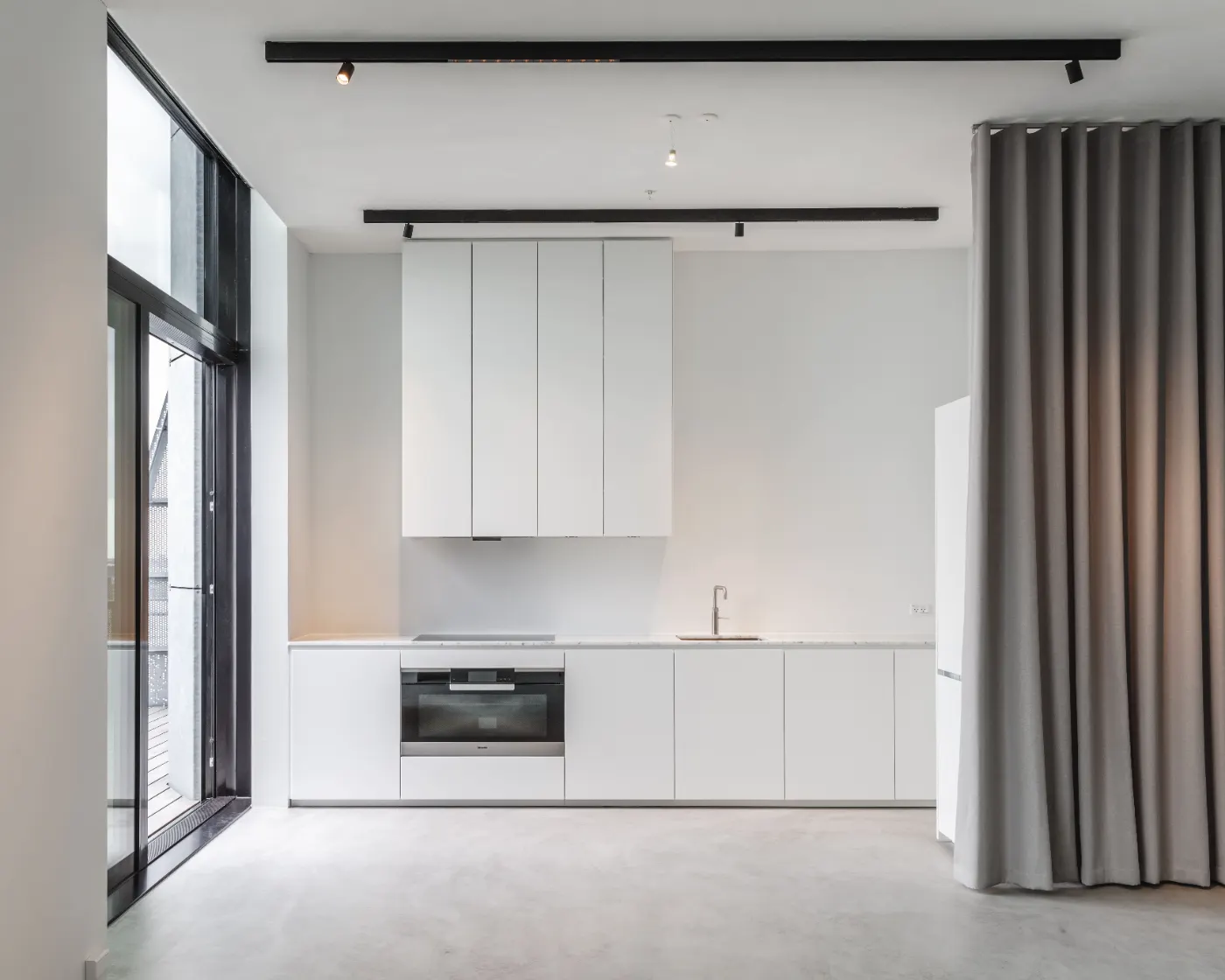 Cucina bianca con pavimento continuo in microcemento