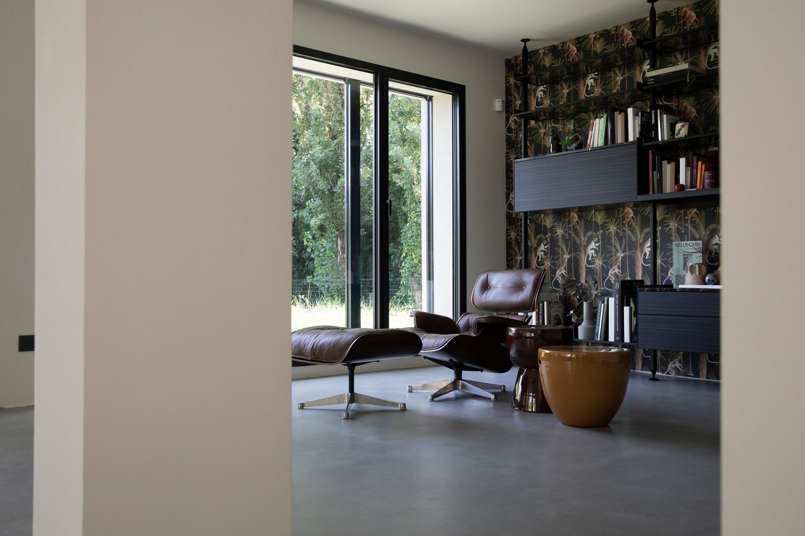 Zona libreria sul gradone in microcemento, con poltrona e parete libreria