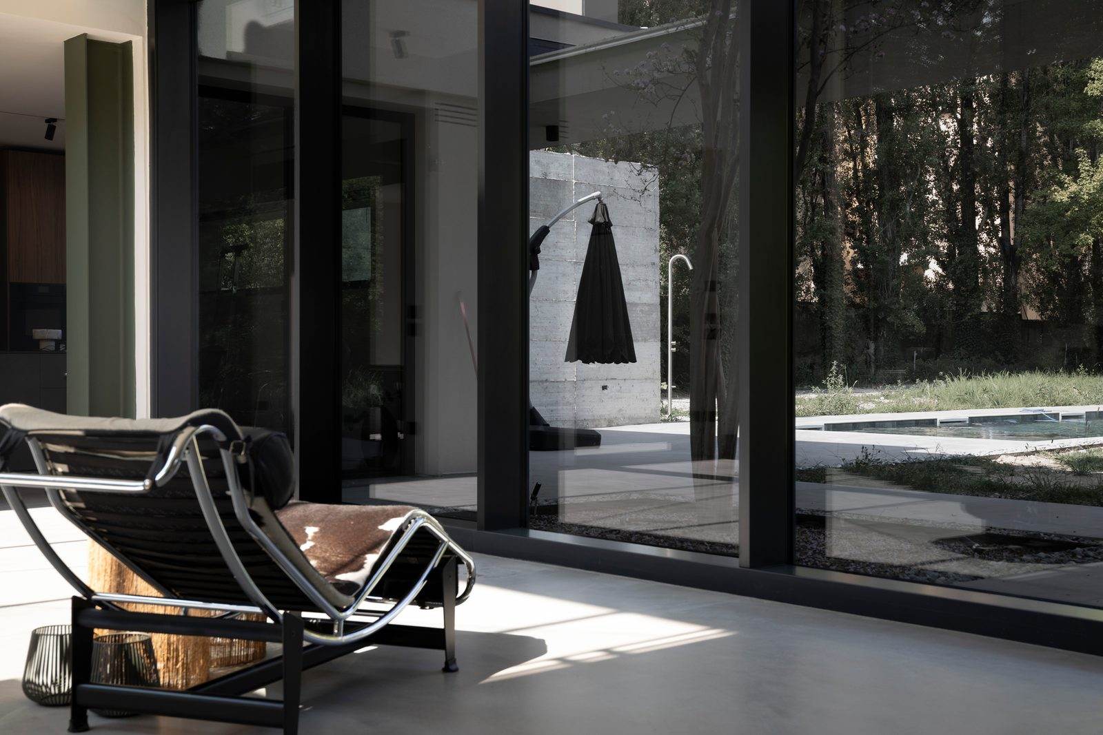 Pavimento in microcemento vicino alla vetrata sul giardino, con chaise longue