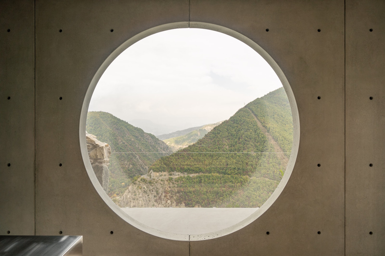 La finestra circolare scavata nel cemento inquadra la valle del Trebbia, casa Vertigo