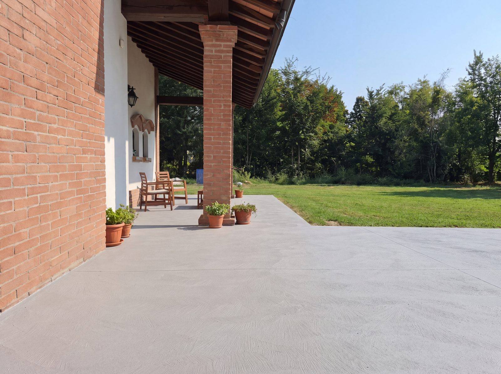 Portico con pavimento in cemento Rasico affacciato sul giardino